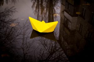 Yellow paper boat floating in a puddle