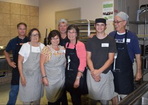 Smiling volunteers wearing aprons standing in the Ray of Hope Community Centre kitchen