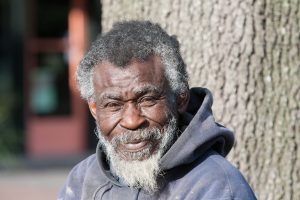 An older black man smiles at the camera