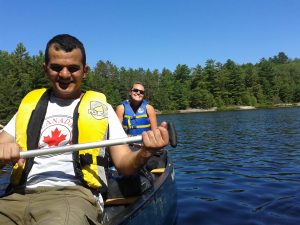 Smiling man and woman paddle a canoe