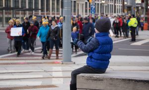 Young boy watches crowd cross at a crosswalk during Ray of Hope's Coldest Night of the Year walk