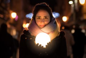 Young woman staring on a dark street holds a glowing ball