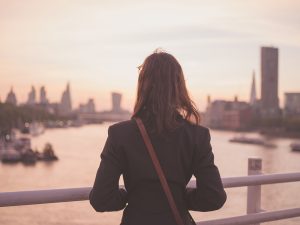 Young woman admiring skyline on a bridge at sunrise