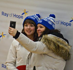 Mother and daughter wearing white and blue CNOY toques take a selfie