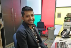 Rupesh sits in fron to a computer at a reception desk