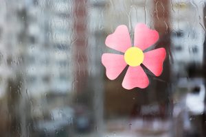 Pink flower sticker on a wet window