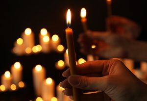 Woman's hand holding burning candle in darkness