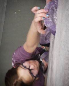 Closeup of young woman reaching for a hold on a climbing