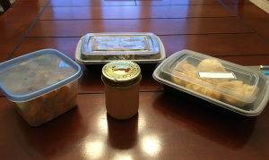 Plastic meal containers sit on a wooden table
