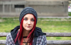 Homeless girl with long red hair sitting alone outdoors