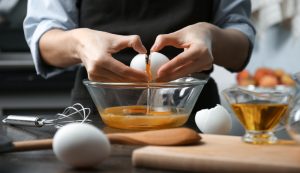 Closeup of a woman's hands as she breaks and egg into a glass bowl