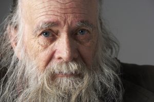 Elderly bearded man looks into the camera