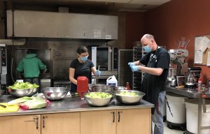 Volunteers prepare salad on a kitchen counter