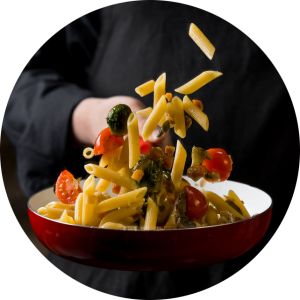 closeup of chef's hands tossing pasta in pan