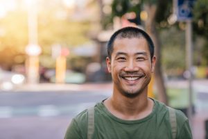 Young Asian man smiling confidently on a city street