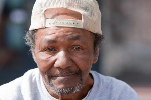 Closeup of older Black man wearing a white baseball cap backward