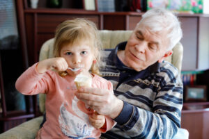 Grandfather sits with his small granddaughter on his lap
