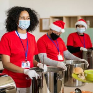 A group of people in red shirts and Santa hats serve food at a soup kitchen